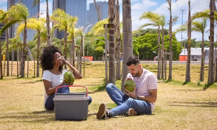 Casal sentado na grama curtindo o dia de sol com a caixa térmica Termolar