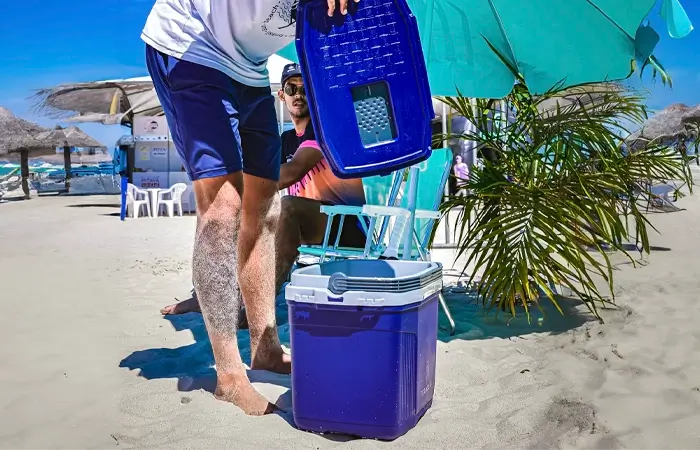 Homem pegando uma bebida gelada na caixa térmica para praia da Termolar